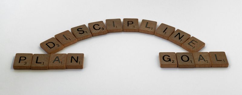 Scrabble tiles spelling out the words 'plan', 'discipline', and 'goal'.