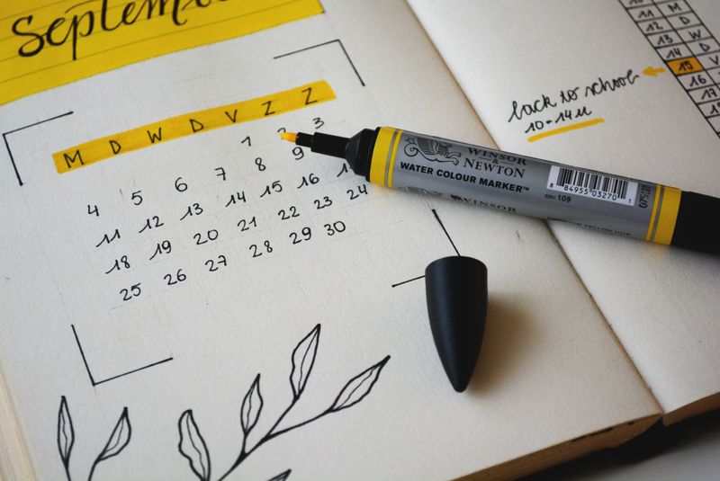 A hand-written calendar with a highlighter sitting on top of it