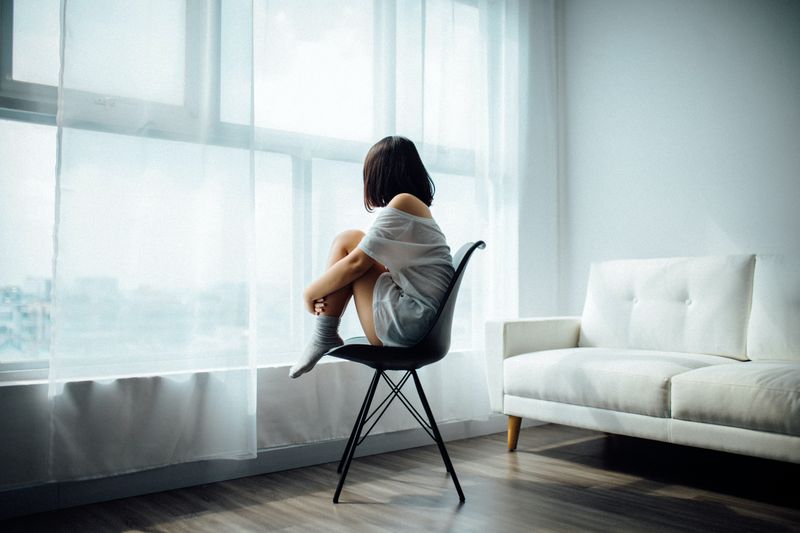 Woman looking out the window while sitting in a chair.