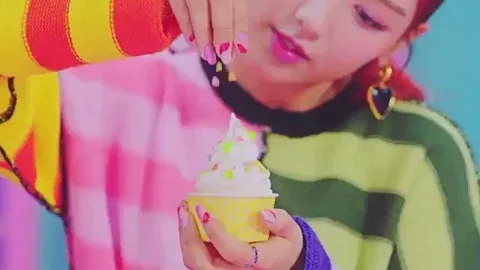 animated gif of woman with pink and red nails sprinkling colorful sprinkles onto a cup of soft serve ice cream