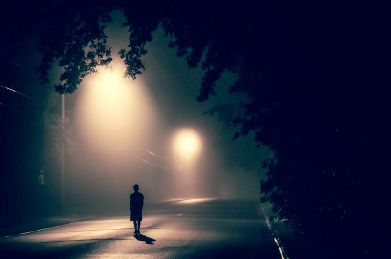 A person walking alone on a dark street.