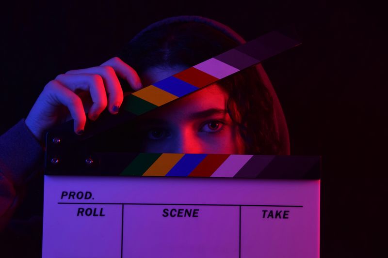 A woman about to close a clapperboard.