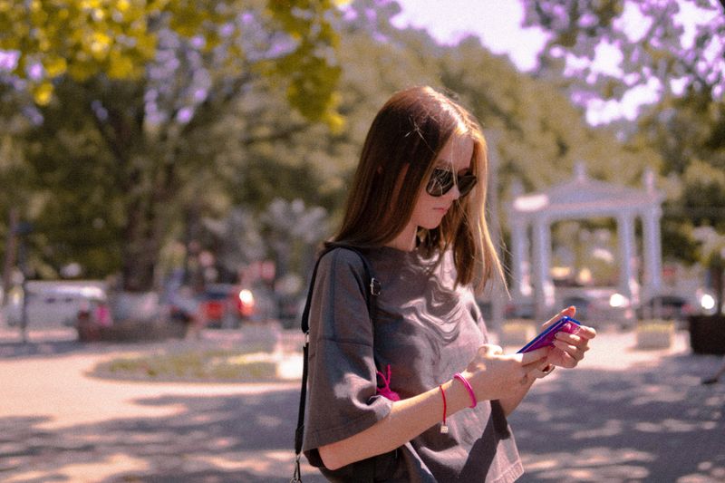 A woman stands outside and looks at her phone