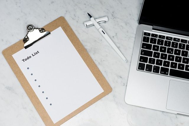 A blank to-do list on a desk beside a laptop and a pen.