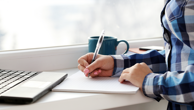 A woman writes in a notebook.