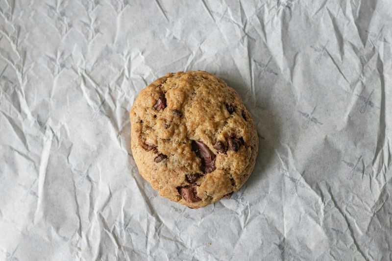 Chocolate chip cookie on top of crumpled up white paper.