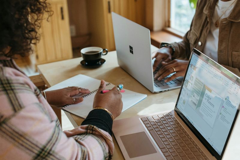 Two people studying together using their laptops on a table. 