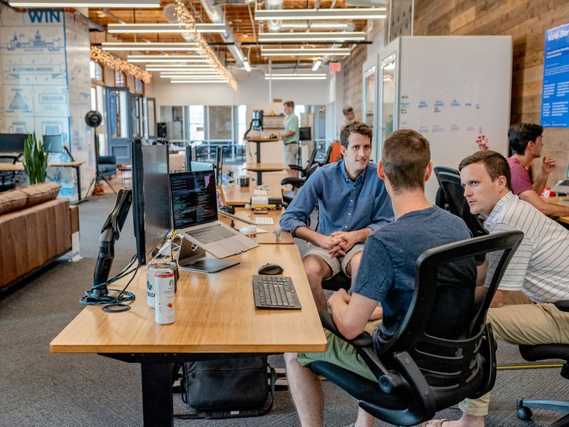 Group of coworkers having a focused discussion in a modern office, demonstrating teamwork and calm communication.
