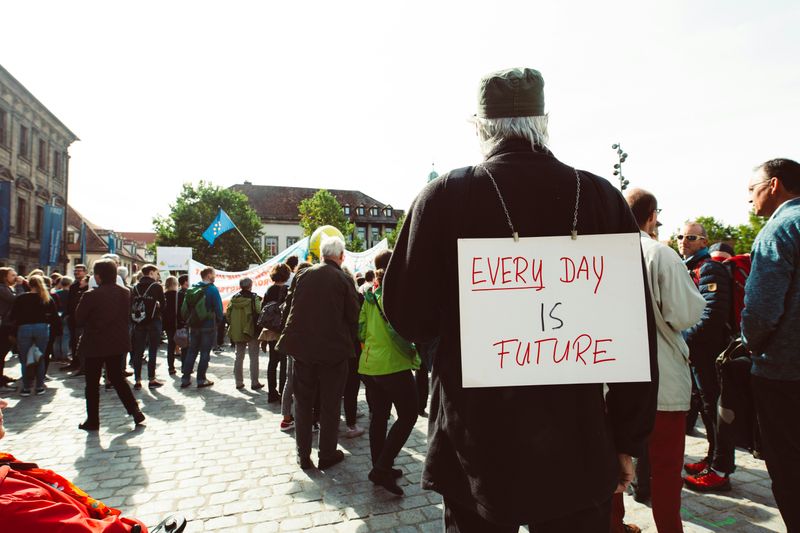 A person at a university campus demonstration. They're wearing a placard that reads, 