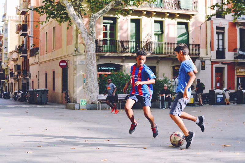 Two kids playing soccer in the street