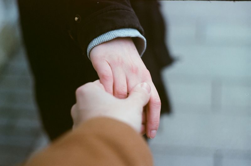 A hand reaching out and holding on to another hand.