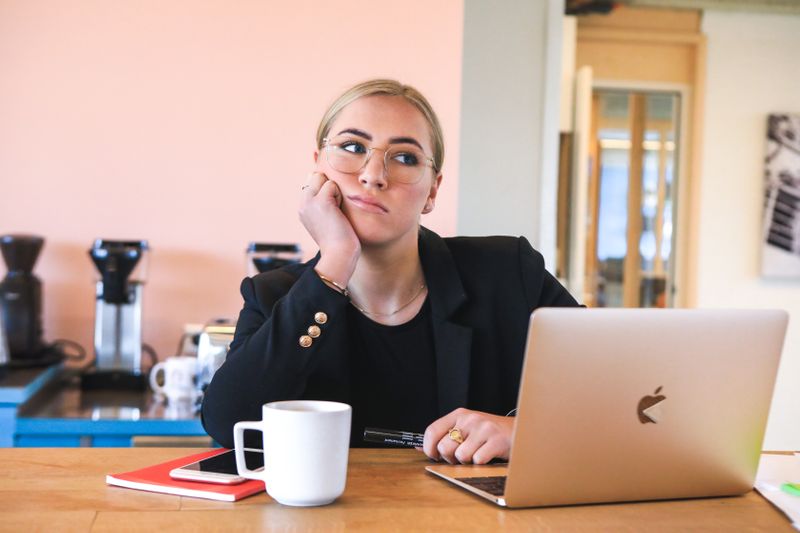 A confused woman sitting in front of a laptop.