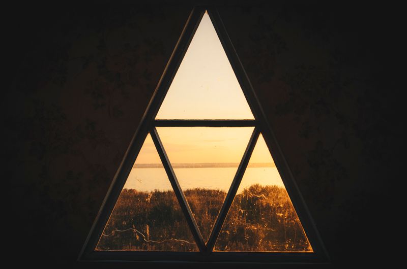 Triangular window looking out to sea and trees