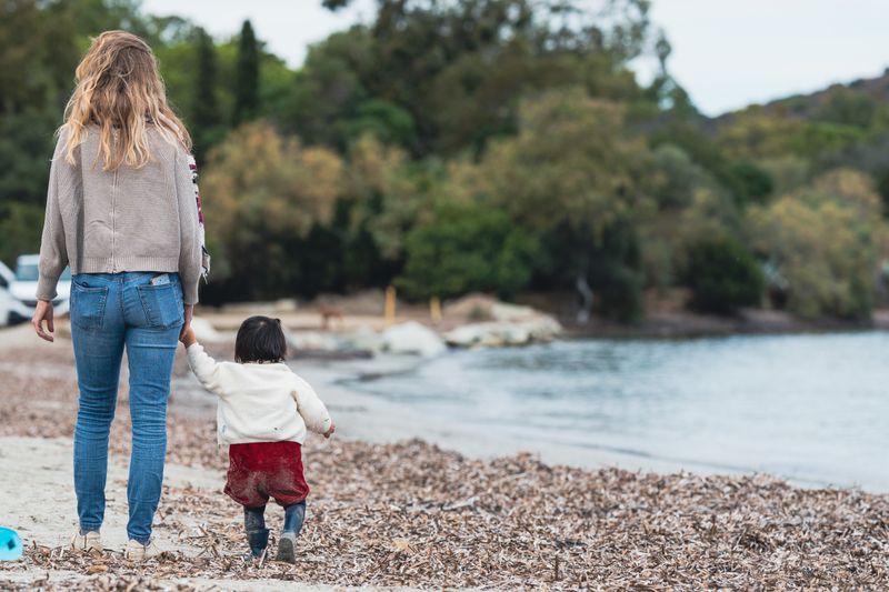 A woman walking on a beach while holding a child's hand