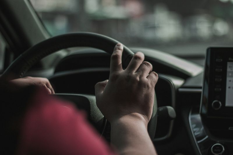 A close shot of the driver of a car behind the wheel.