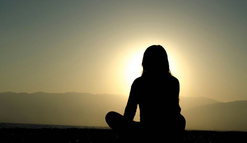 A woman meditating in the mountains at sunrise.