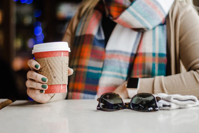 Person holding disposable coffee cup sitting at table