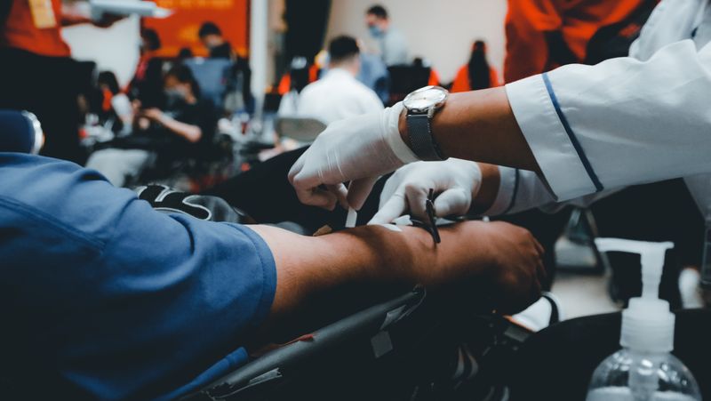 Close up image of a patient holding out his hand while a medical professional with gloved hands treats him.