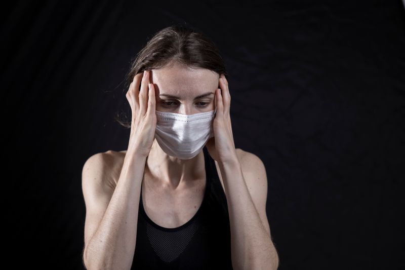 A person wearing a medical mask looking stressed