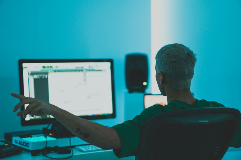 A music producer looking at computer with arms out.