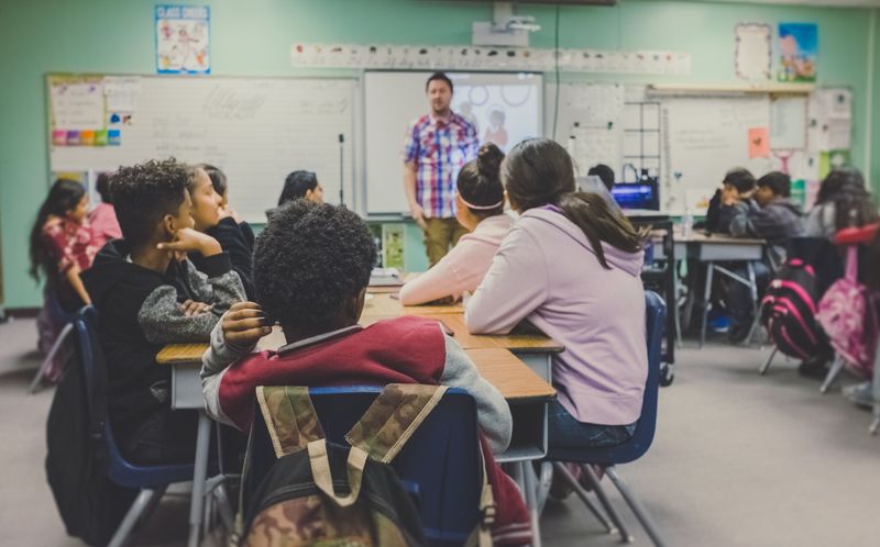 students in a classroom with a teacher at the front of the room