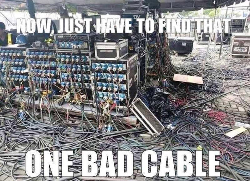 An audio setup at a festival. Cables litter the ground. The text reads, 'Now, just have to find that one bad cable.'