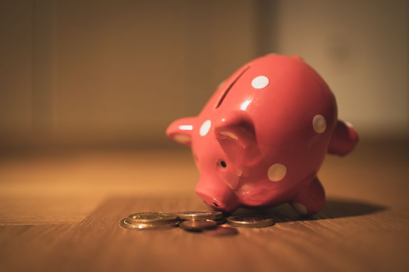 A piggy bank on a desk. A few pennies are scattered around it.