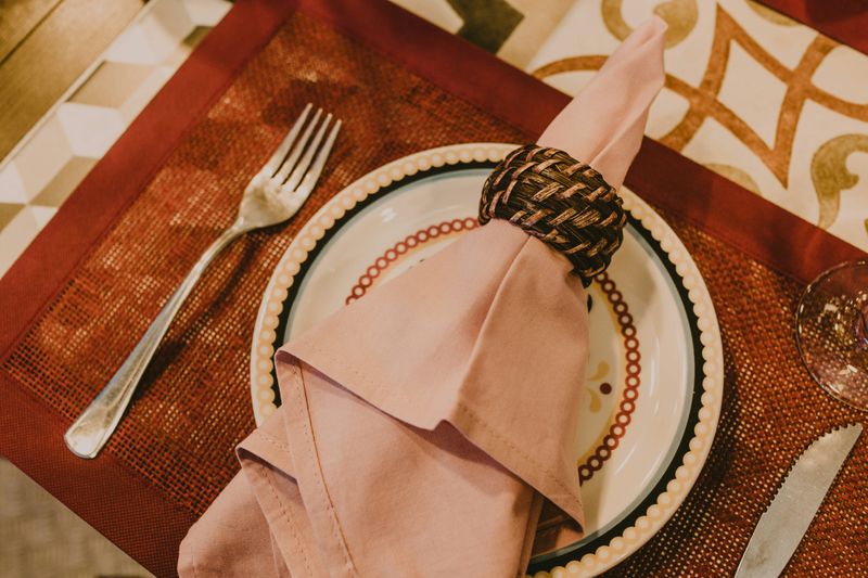 A table setting with a cloth napkin in a ring on a plate.