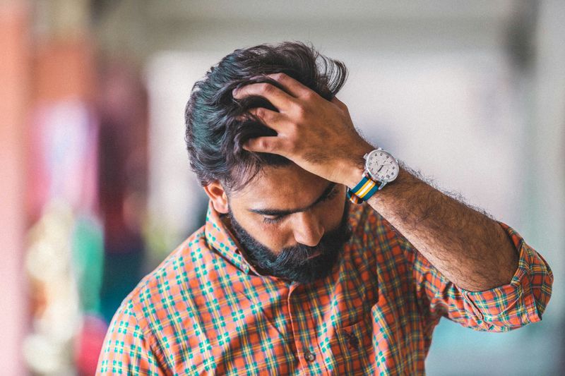 Man looking down with his hand in his hair