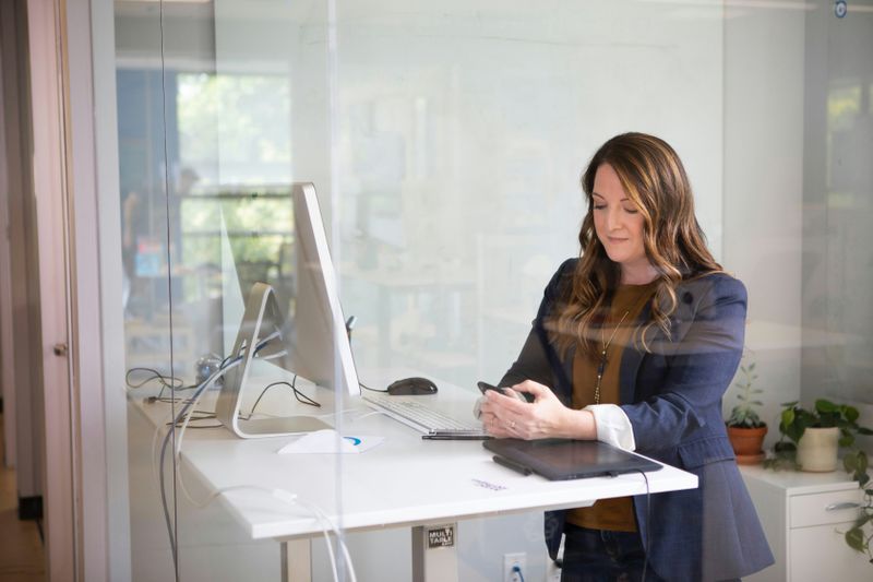 A woman at a standing desk, working and looking satisfied. 