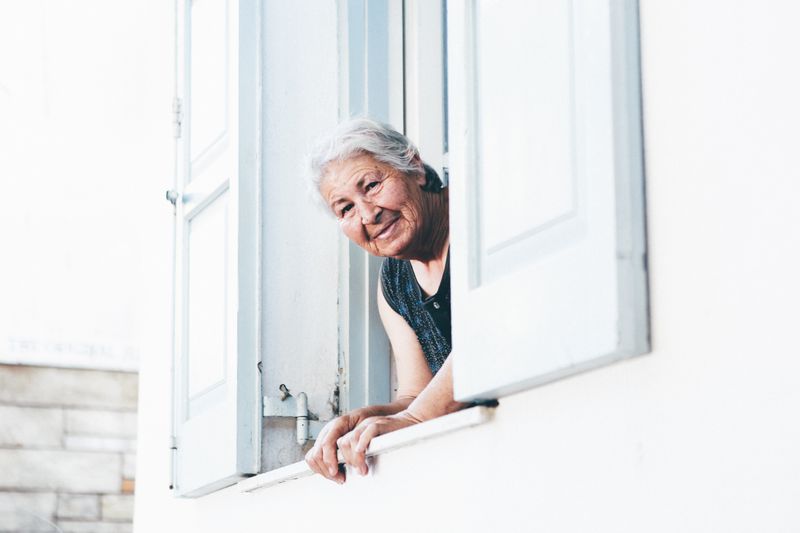 An elderly woman looking out of a window