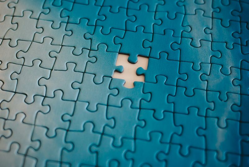 A blue jigsaw puzzle with one piece missing near the center.