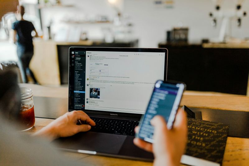 An employee using AI for HR tasks at a desk, with a laptop and phone.