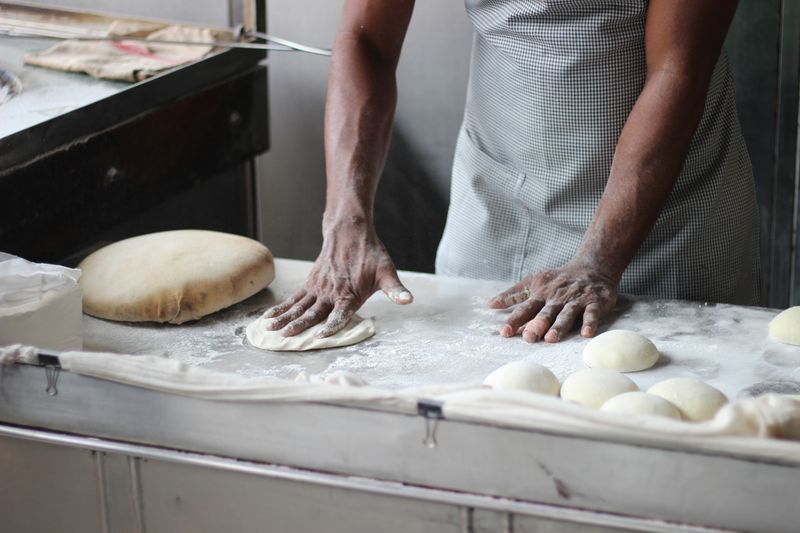 A cook making pizza dough on a kitchen counter.