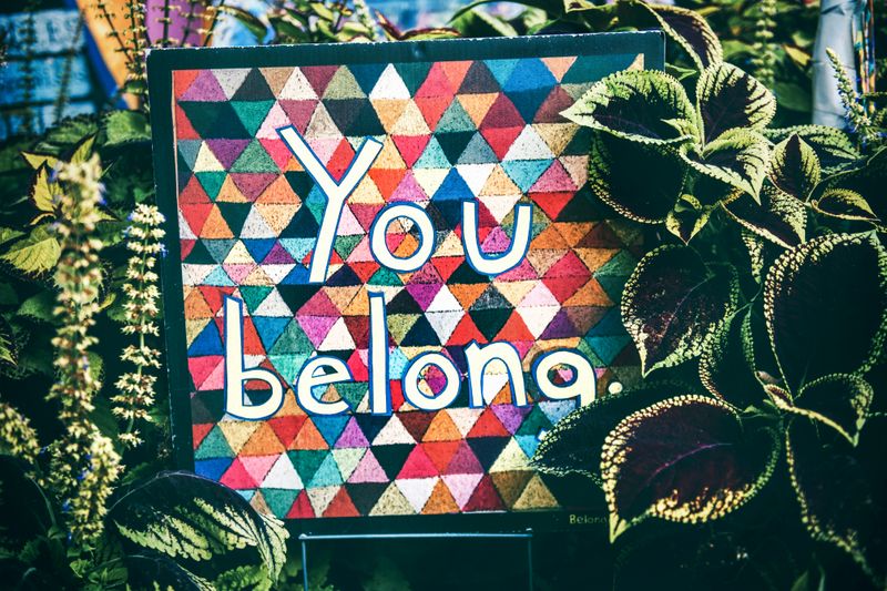 A colorful tiled mural in a garden that reads: 