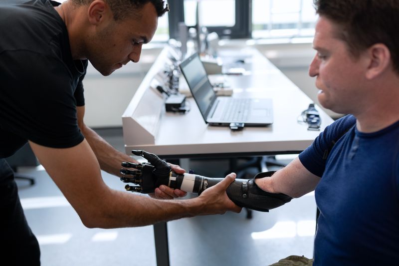 Therapist helping patient with disability affecting arm (prosthetic).