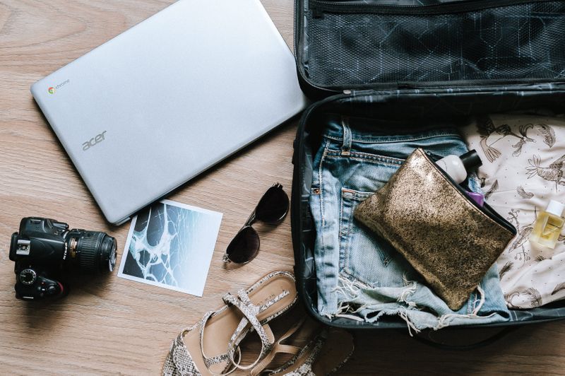 A travel bag with a laptop, camera, makeup bag, and clothes.