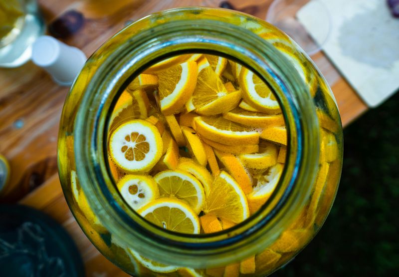 Looking into a big jar full of sliced lemons on a countertop.