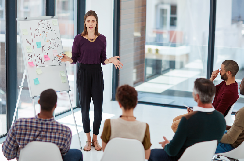 A young woman presenting in front of a group of people.