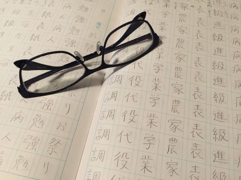 A book of kanji practice with eyeglasses on top of a page.