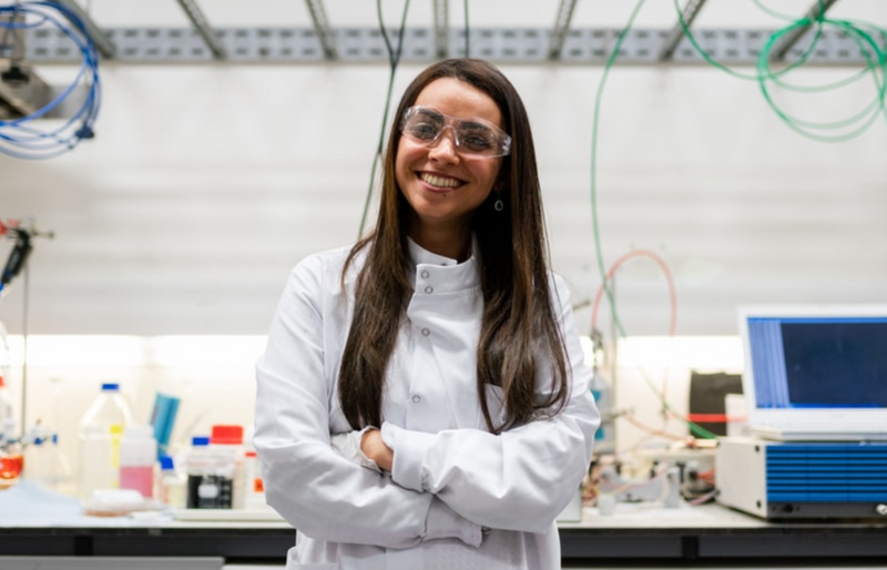 Woman in lab coat leaning against counter