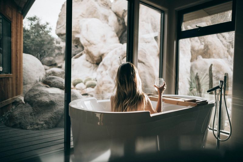A women sitting in the bathtub with a glass of wine