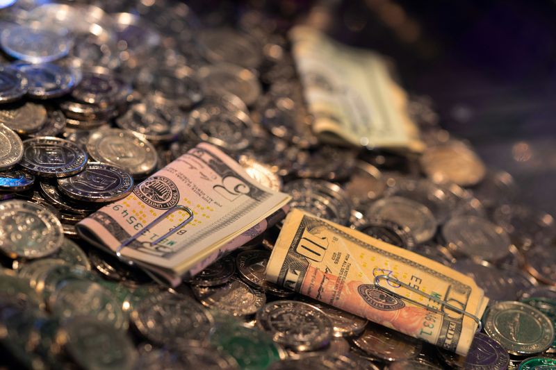 Three money rolls of folded money paper notes laying on a bed of coins 