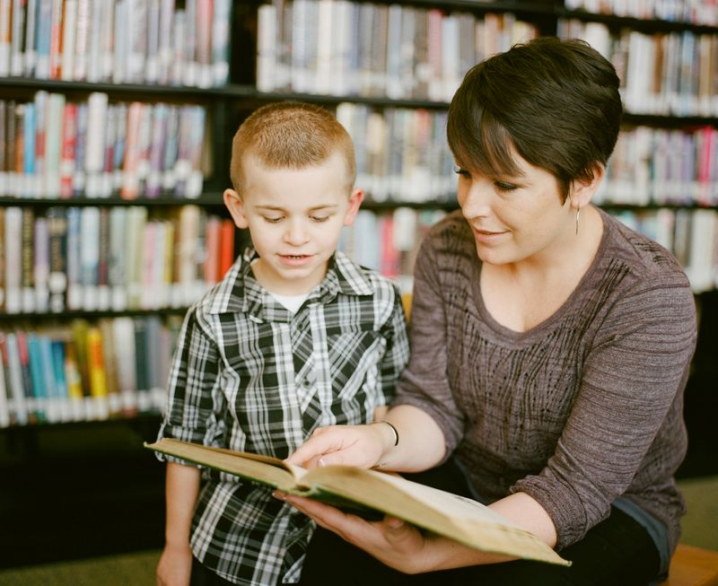 A woman helping a child read a book.