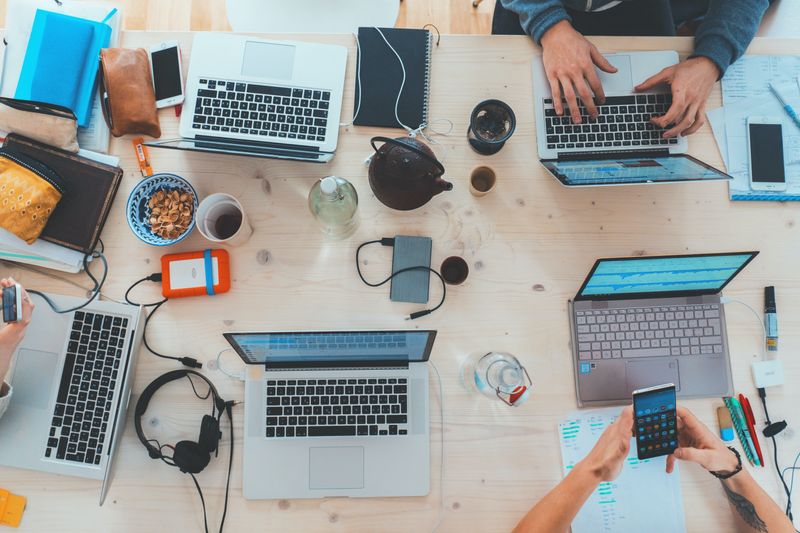 A group of people working with their laptops and devices at a shared desk