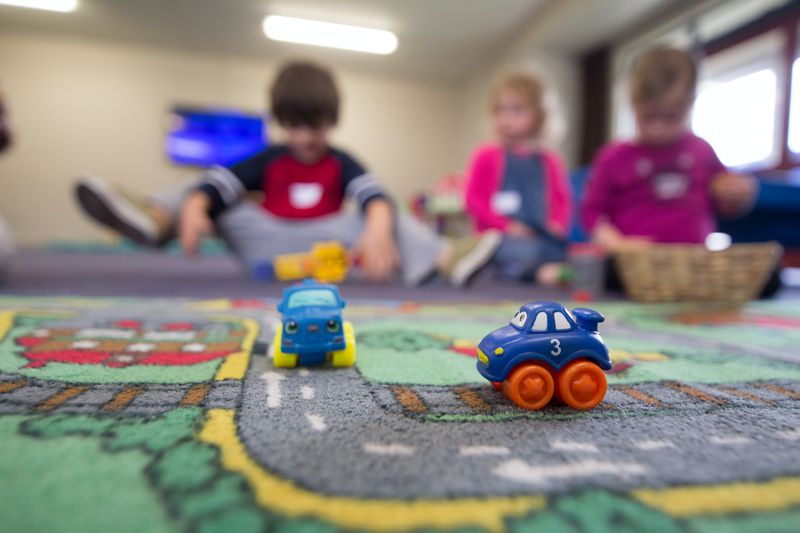 Preschool children playing with cars on carpet.
