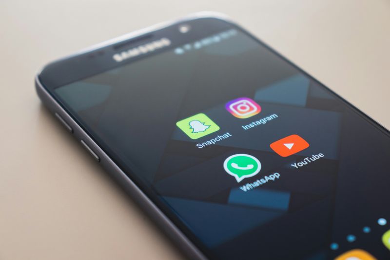 An image of a Samsung phone with logos for the apps SnapChat, Instagram, WhatsApp and YouTube on screen.