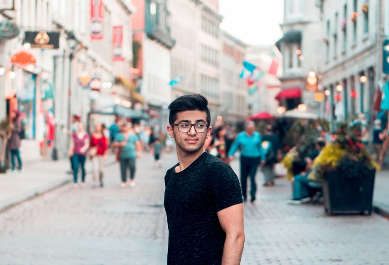 A teenage boy stands on a city street.