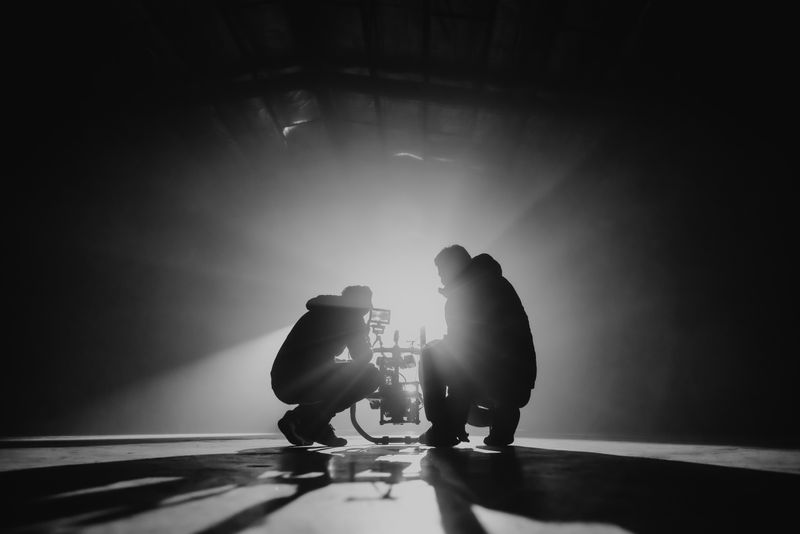 Two people crouched down staring through a camera at a scene. Photo by Natalie Parham on Unsplash