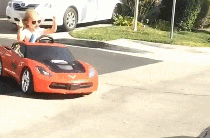 A child in their toy, sport's car sliding from a driveway into the road.